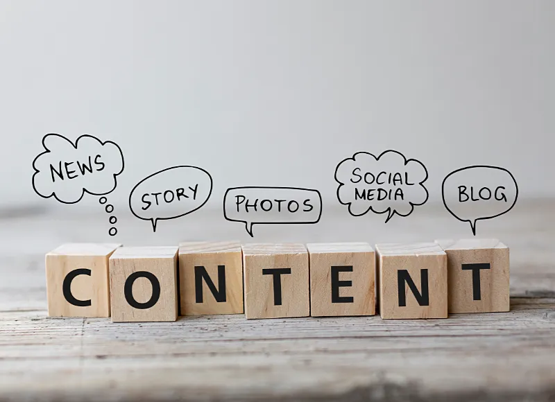 Das Wort "content" aus Holzbuchstaben, dazu Sprechblasen mit Wörtern aus der Content-Strategie